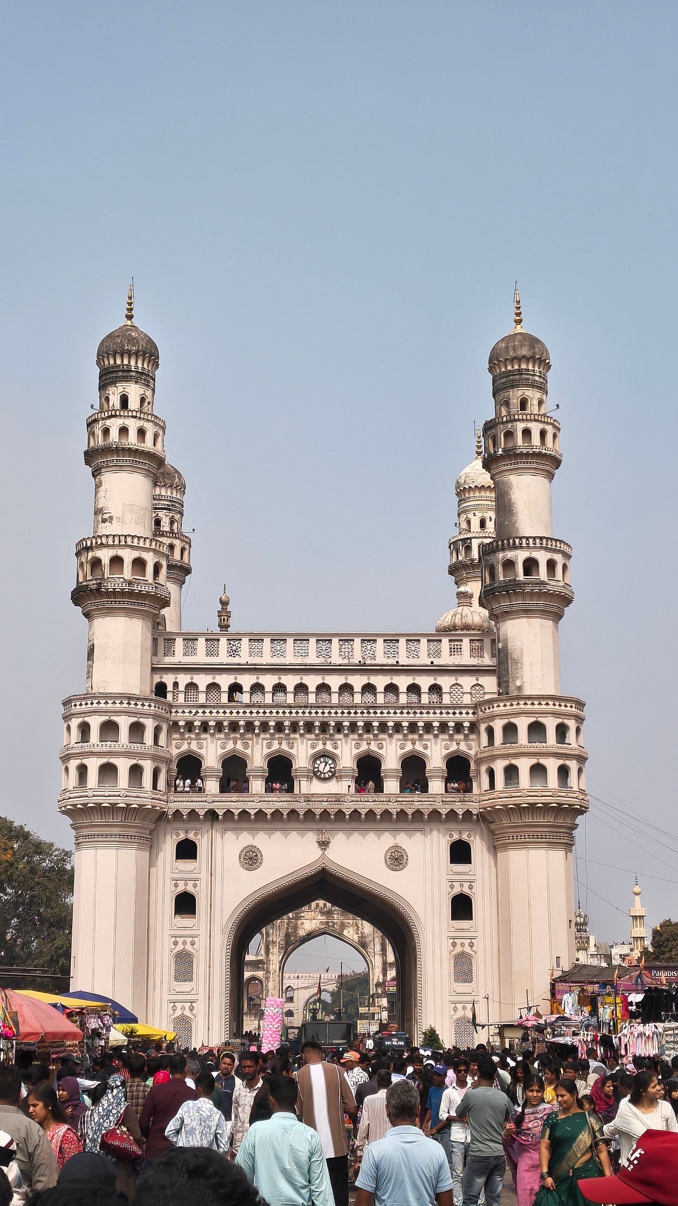 Charminar against a clear sky, with a crowd at its base