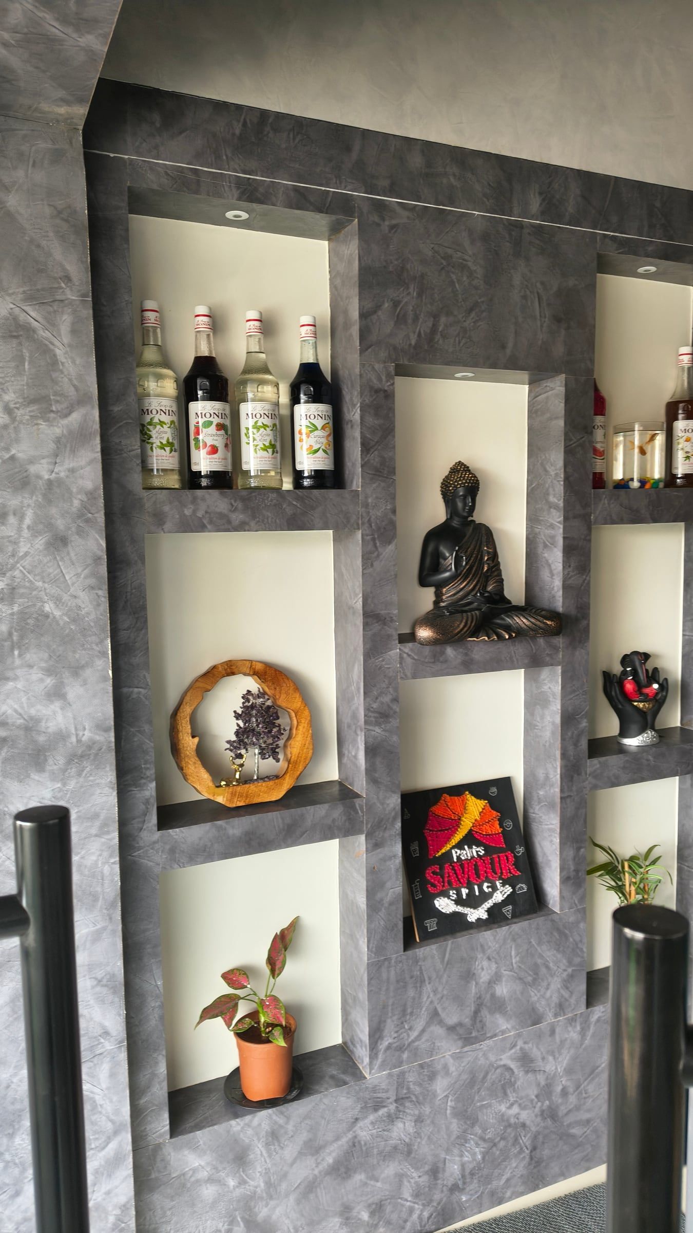 Wall shelves with bottles, a small statue and plants