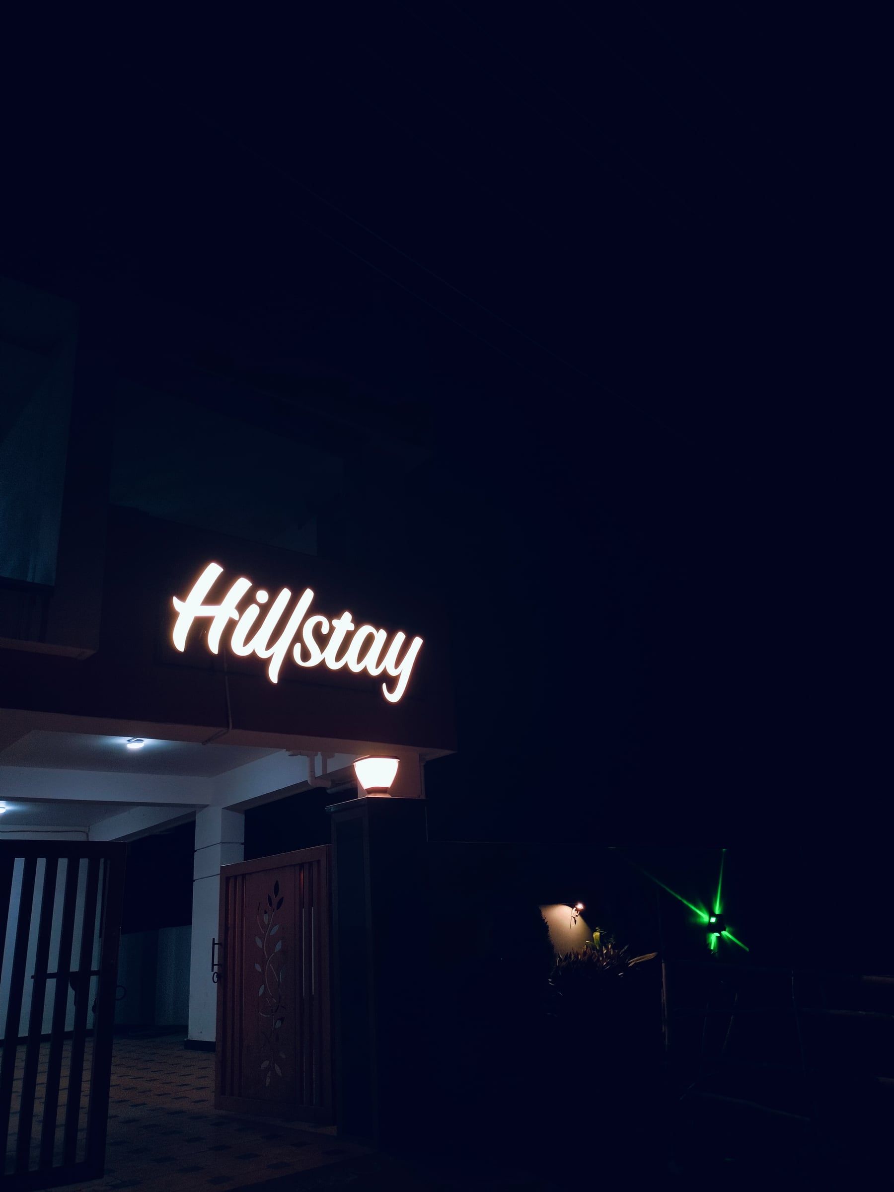 A glowing Hillstay sign on a building at night