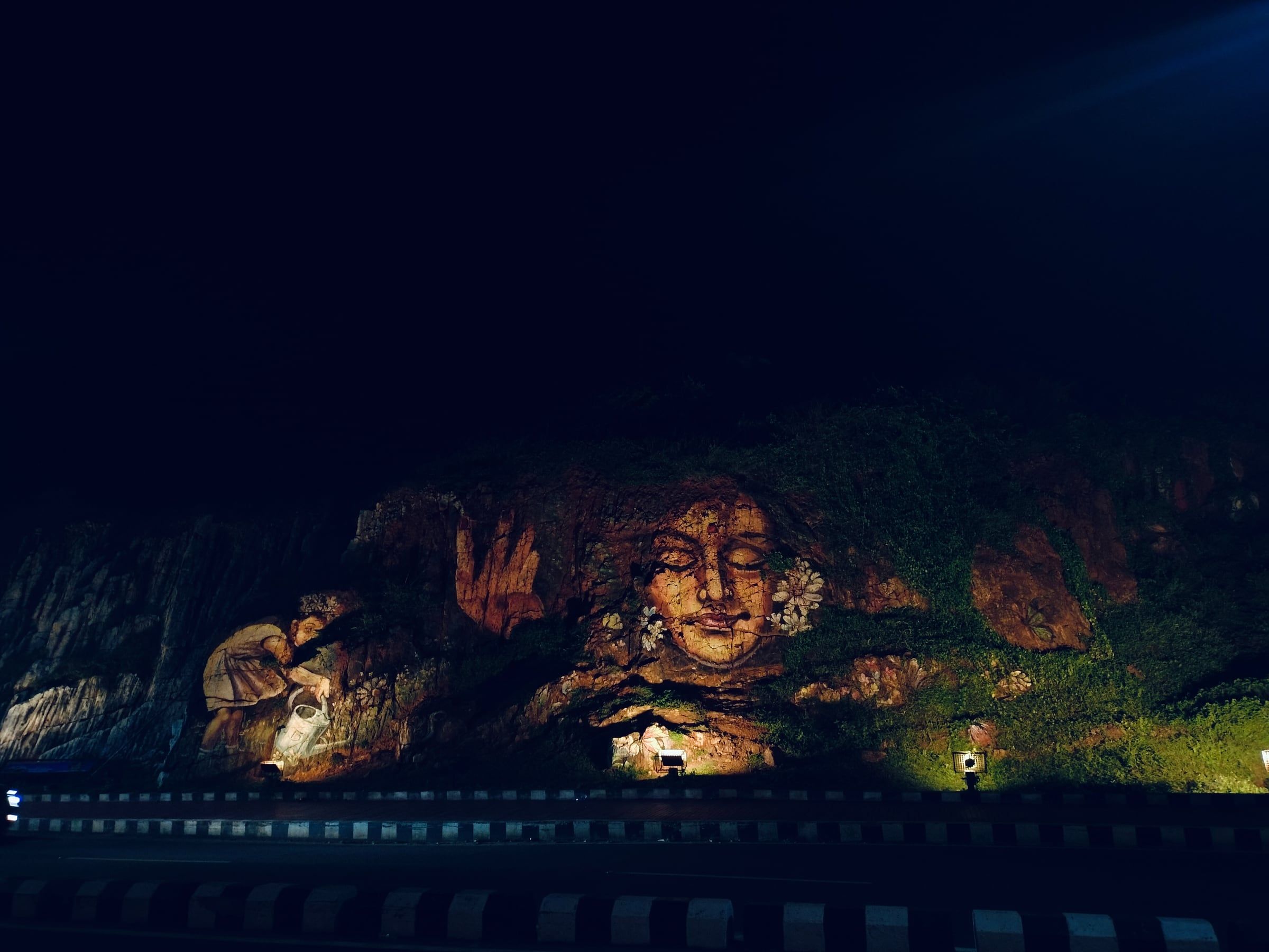 A face carved into rock, lit up at night